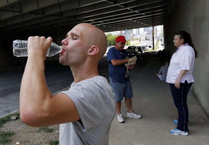Terry Teague (background) of our Bible Study handing out water and cards to a couple living on the street. (Photo courtesy of Tulsa World)